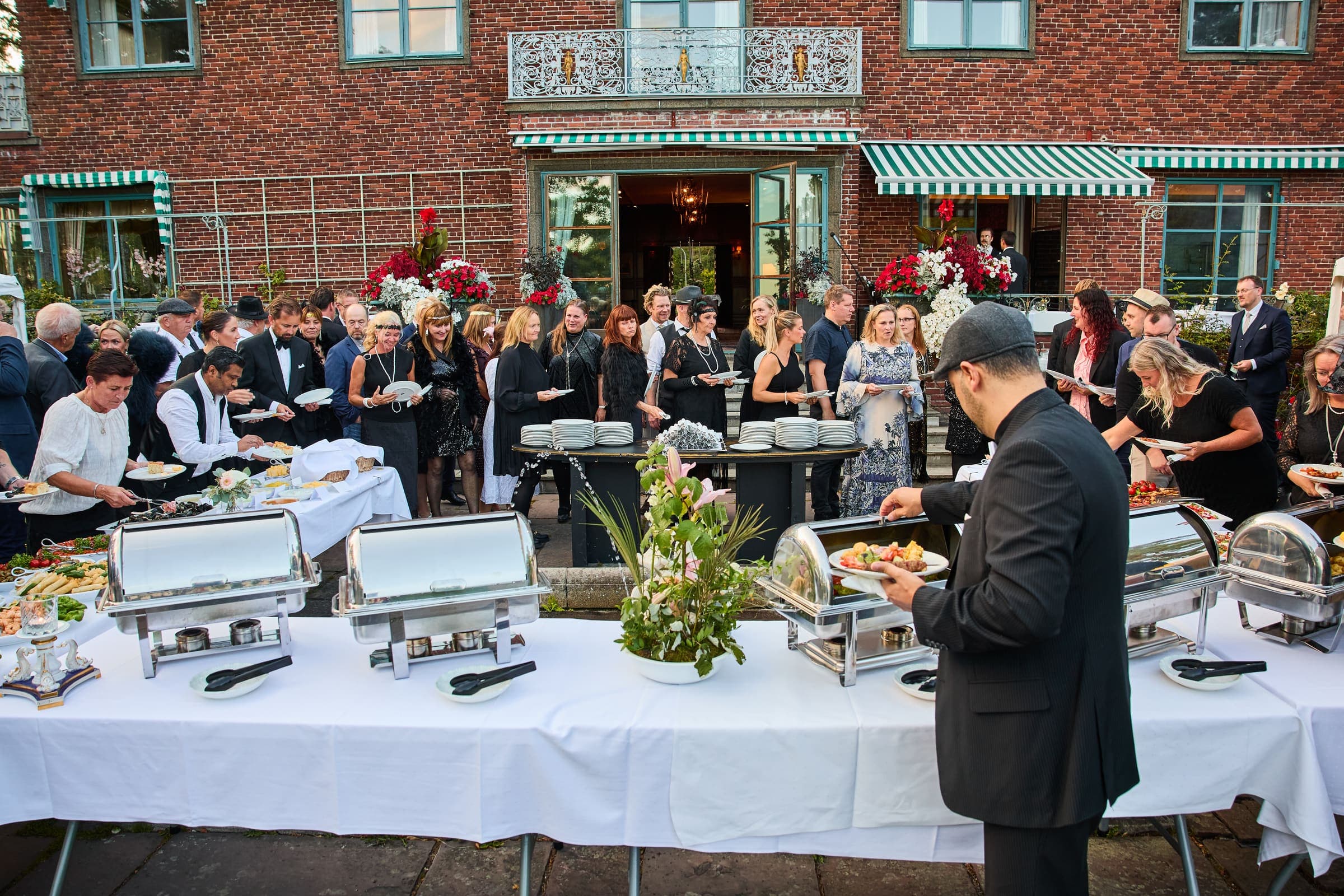 Gjester samlet rundt buffeten i hagen under et firmaarrangement